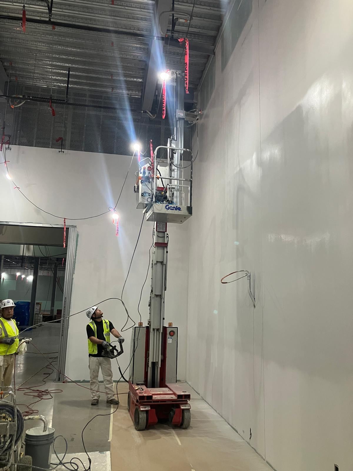 RSX Painter with extended pillar spraying a wall in a data center under construction