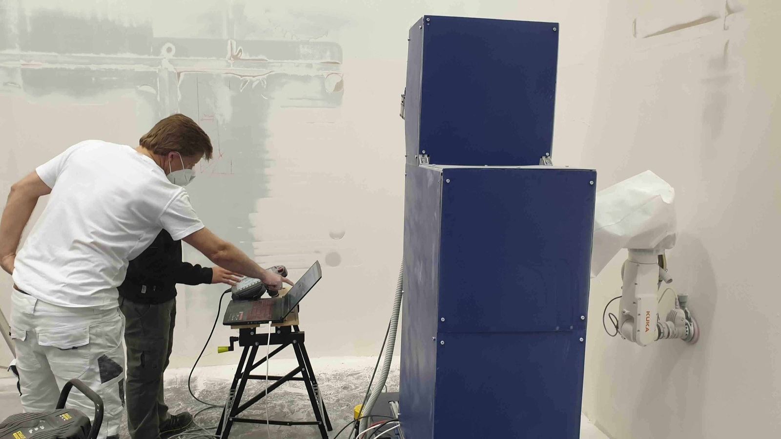 Robosurf Wizard sanding a wall, operator at the control laptop